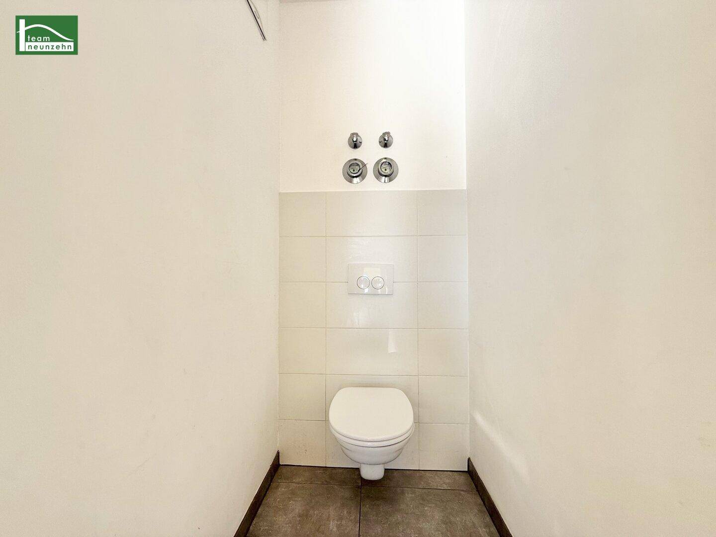 Separates WC mit wandhängender Toilette und modernen Fliesen am Boden.