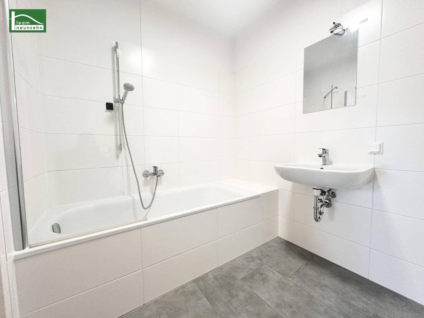 Modernes Badezimmer mit Badewanne, Waschbecken und weißen Fliesen an den Wänden.