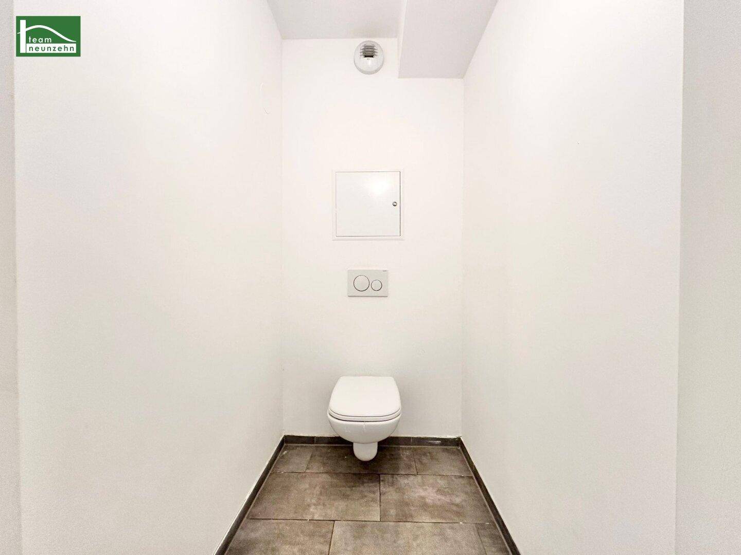 Kleines, separates WC mit Wand-WC und dunklen Fliesen.