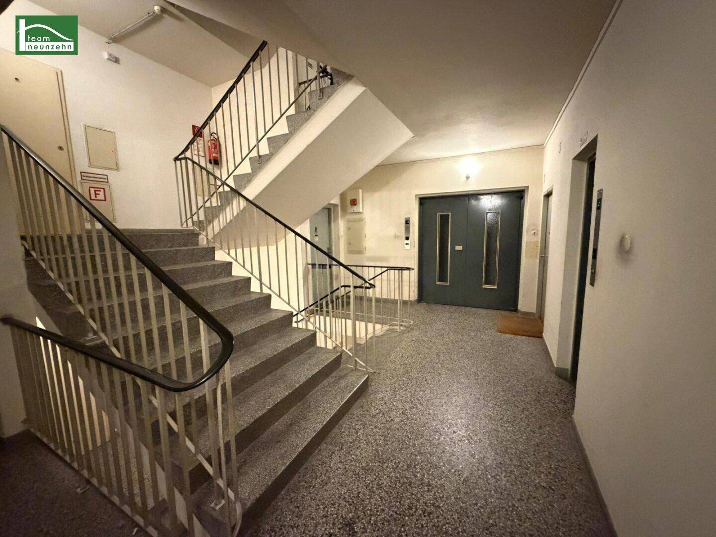 Treppenhaus mit Aufzug und Terrazzoboden in einem Mehrfamilienhaus.