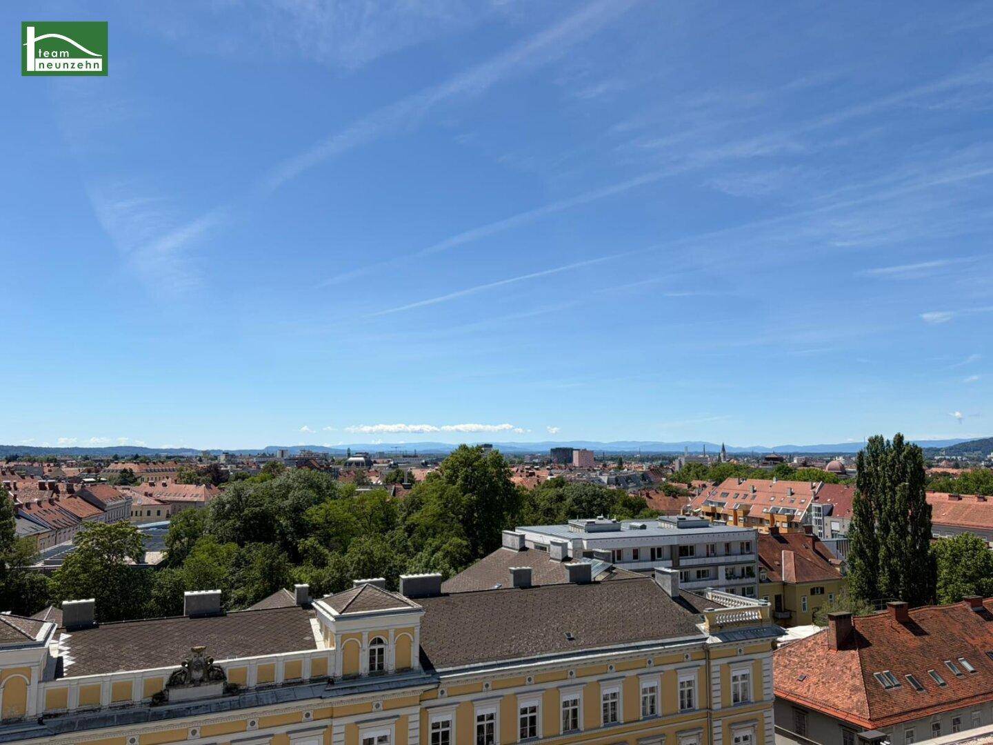 Breiter Ausblick über die Stadt mit blauen Bergen am Horizont.