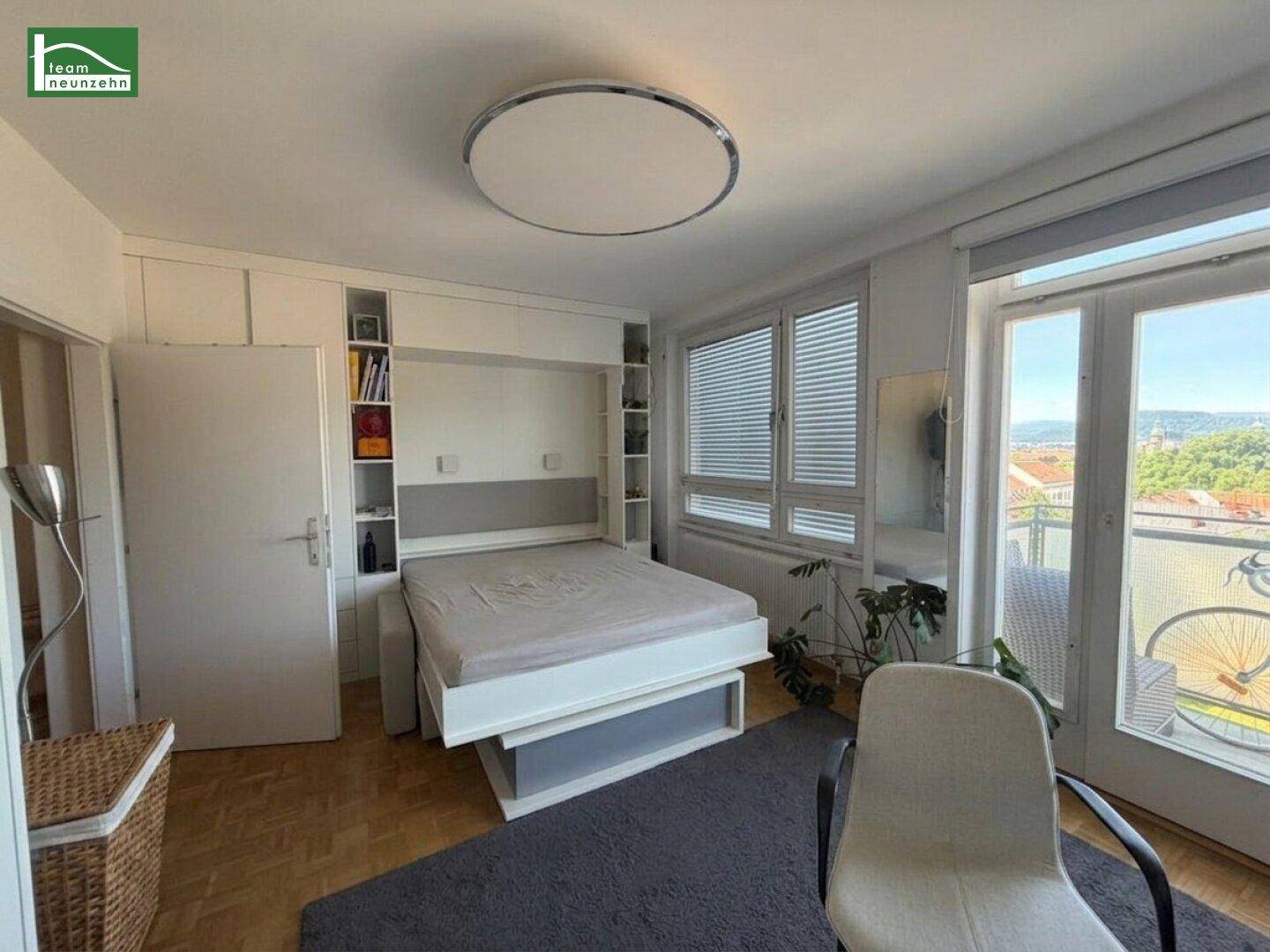 Schlafzimmer mit integriertem Wandbett, Parkettboden und Zugang zum Balkon.