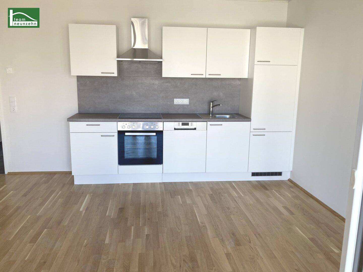 Moderne Einbauküche in Weiß mit integrierten Geräten und Holzparkettboden.
