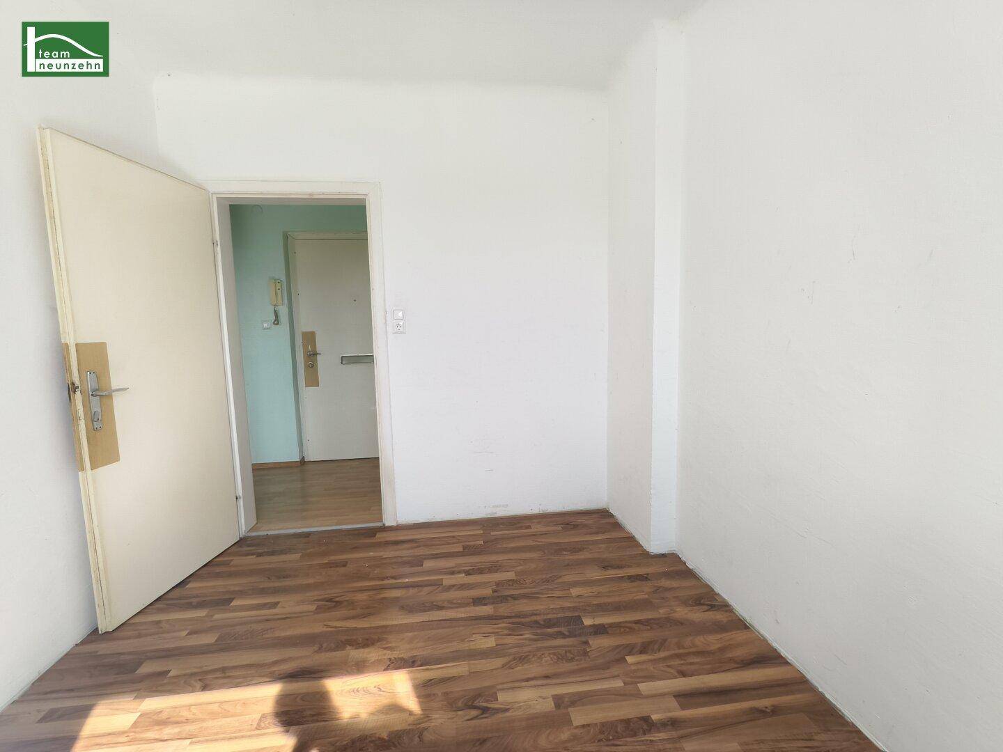 Eingangsbereich oder Flur mit Laminatboden und weißen Wänden, der zu weiteren Räumen führt.