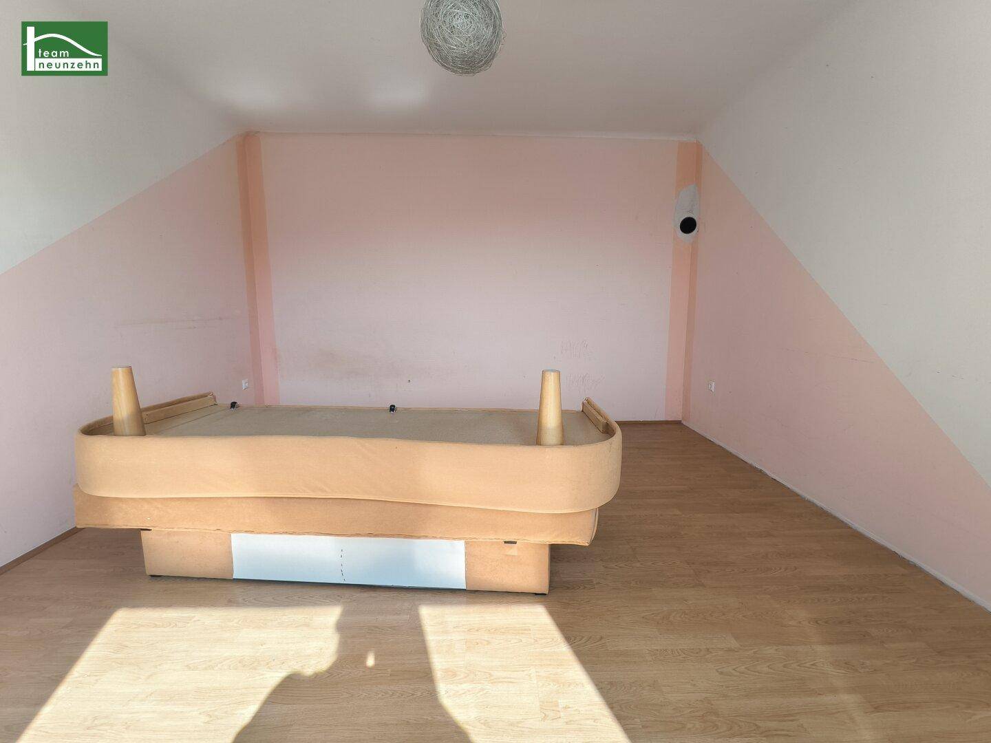 Helles Schlafzimmer mit Laminatboden und einer auffälligen rosa Wandgestaltung.