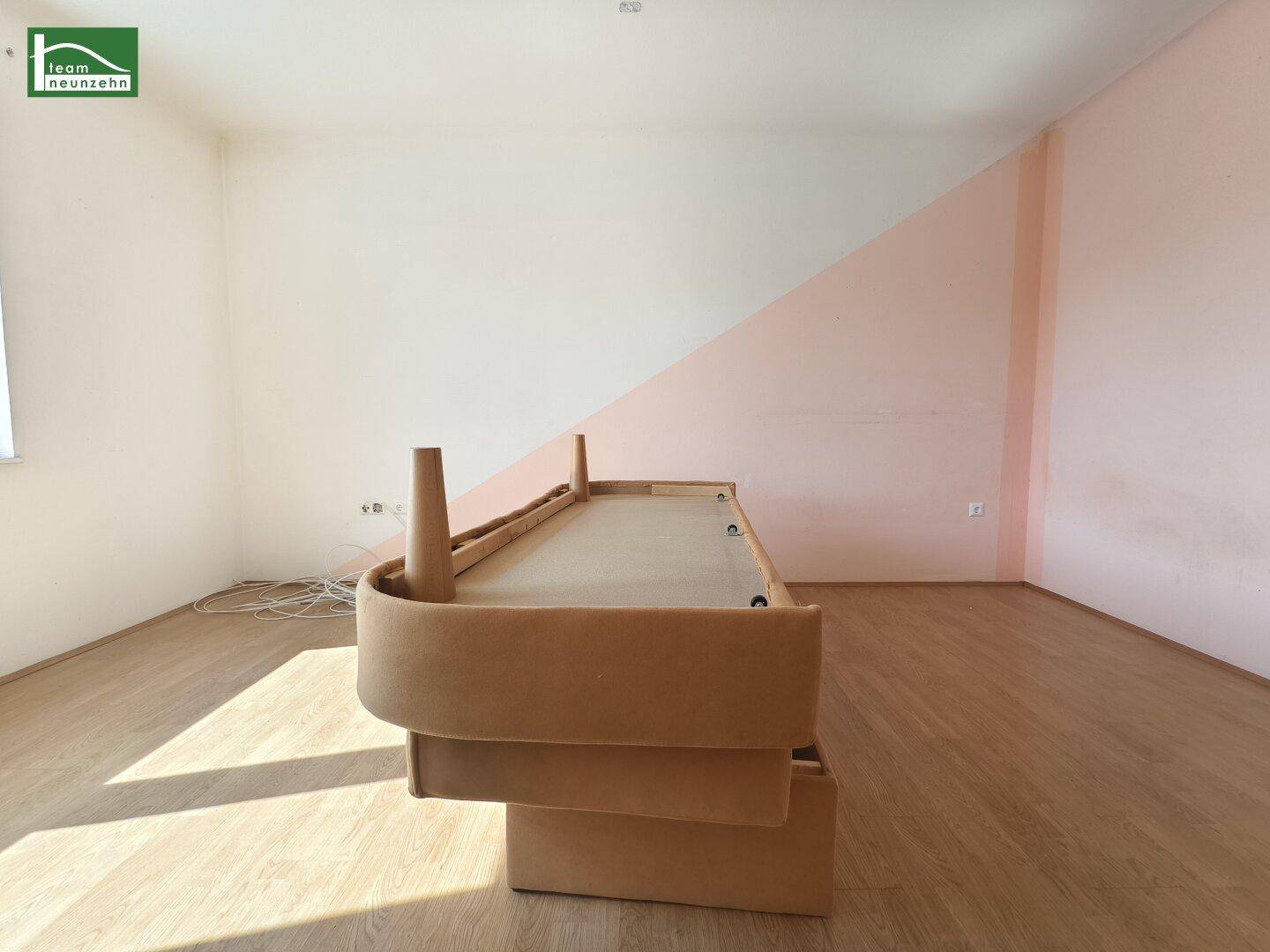 Geräumiges Schlafzimmer mit Holzboden und einer modernen, zweifarbigen Wandgestaltung.