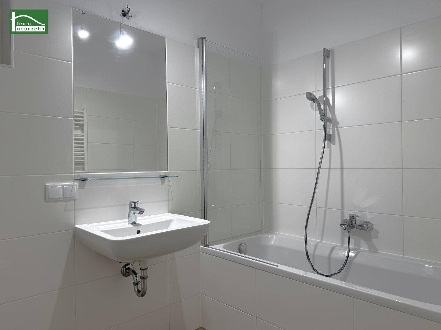 Modernes Badezimmer mit Badewanne, Dusche, Einzelwaschbecken und weiß gefliesten Wänden.