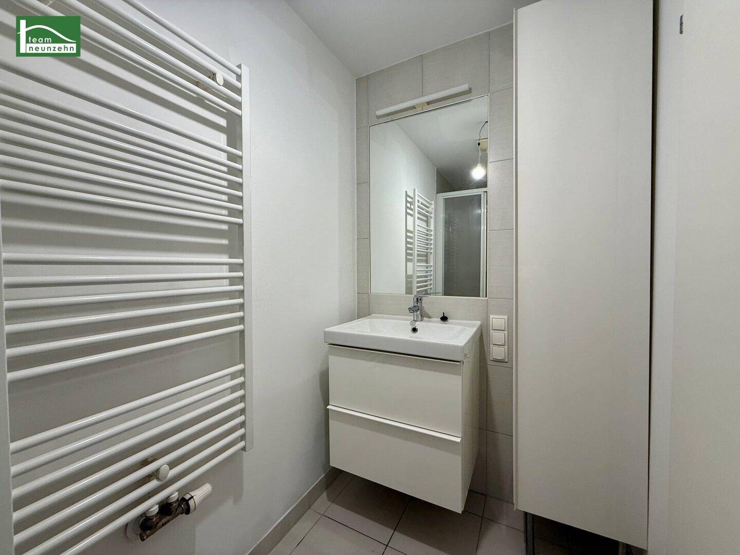 Modernes Badezimmer mit Waschtisch, Spiegel und beheiztem Handtuchhalter.