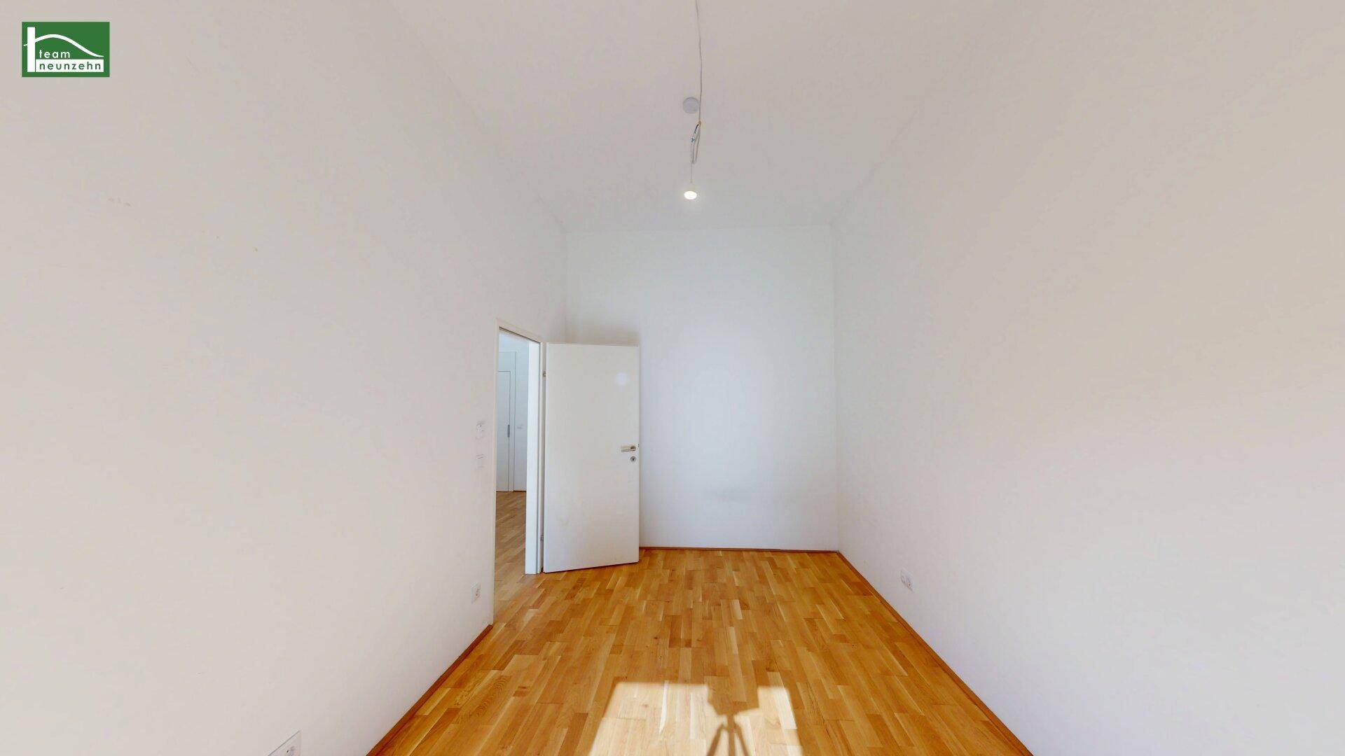 Leeres Zimmer mit hellem Parkettboden und weißen Wänden, bereit zur individuellen Gestaltung.