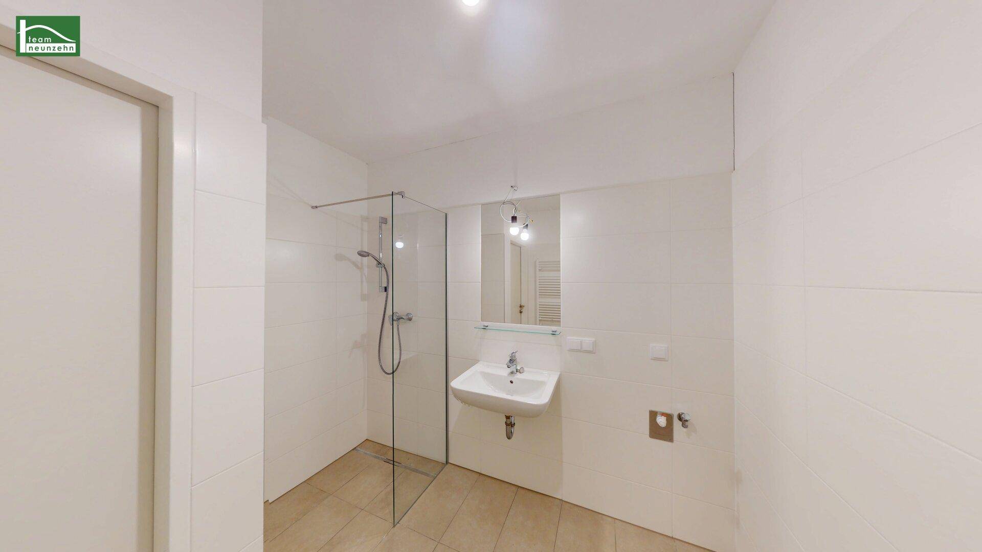 Modernes Badezimmer mit begehbarer Dusche, weiß gefliesten Wänden und Einzelwaschbecken.
