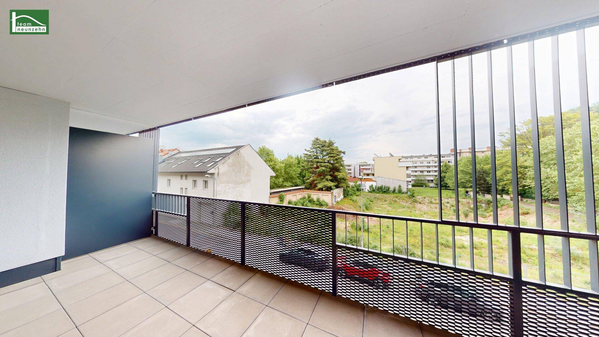 Moderner Balkon mit Metallgeländer und weitem Blick über die Stadt und Natur.