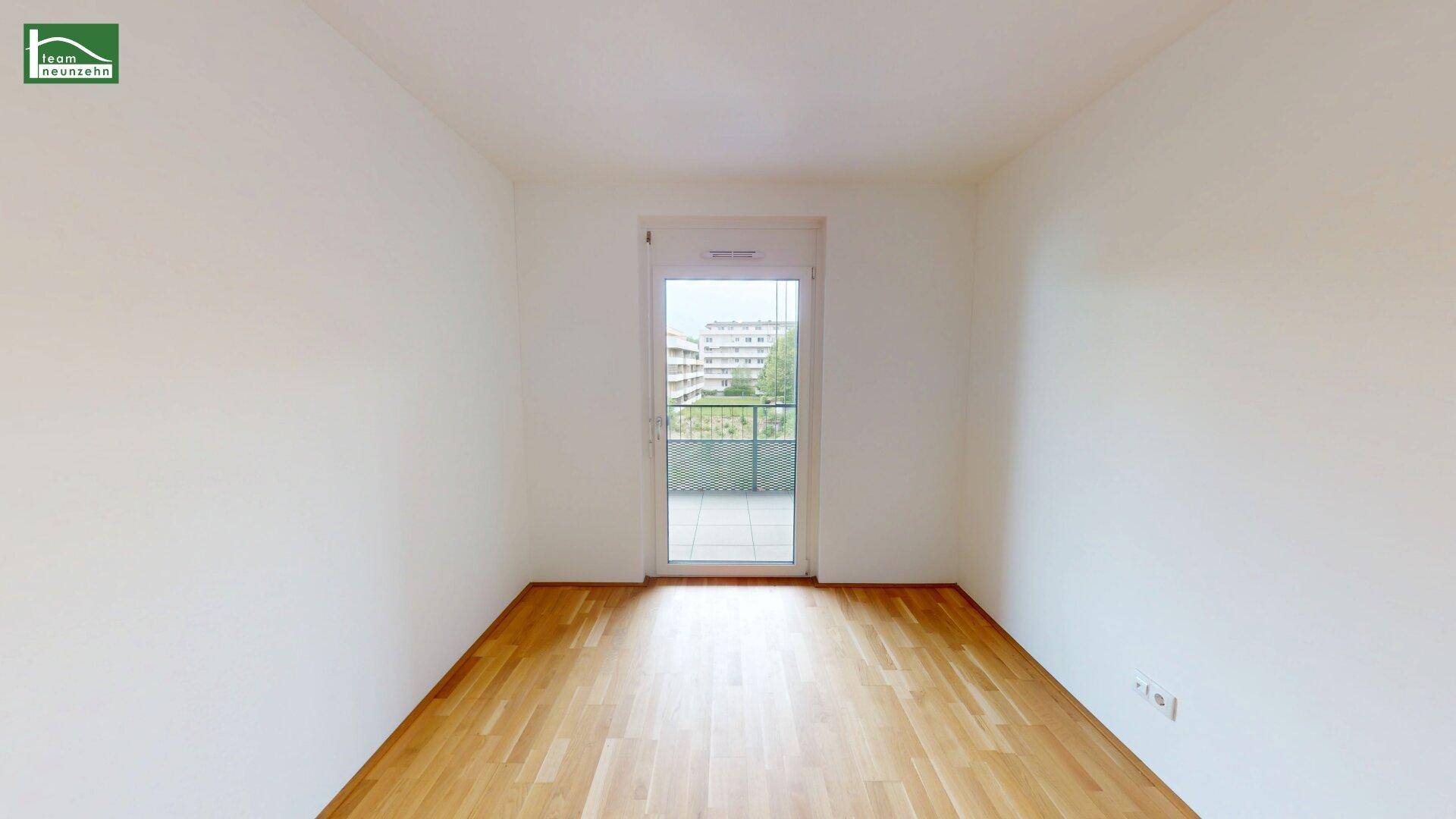 Helles, unmöbliertes Zimmer mit Holzboden und Zugang zu einem Außenbereich.
