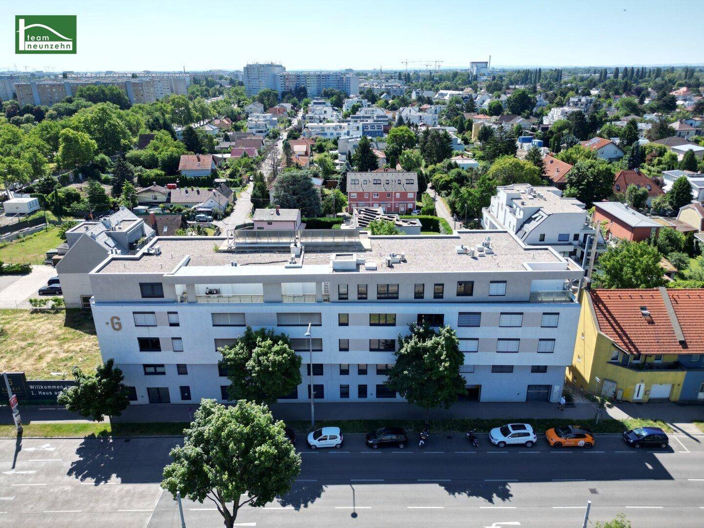 Moderne Wohnanlage mit Flachdach und Balkonen in grüner Stadtrandlage, umgeben von weiteren Wohnhäusern.
