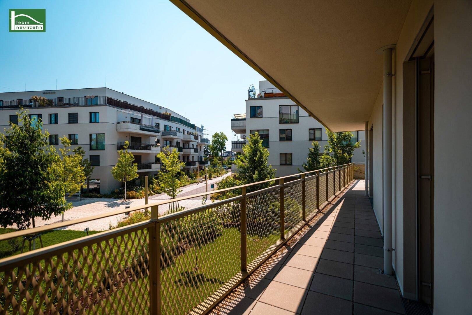 Langer Balkon mit Metallgeländer und Blick auf die Straße und die Wohngebäude.