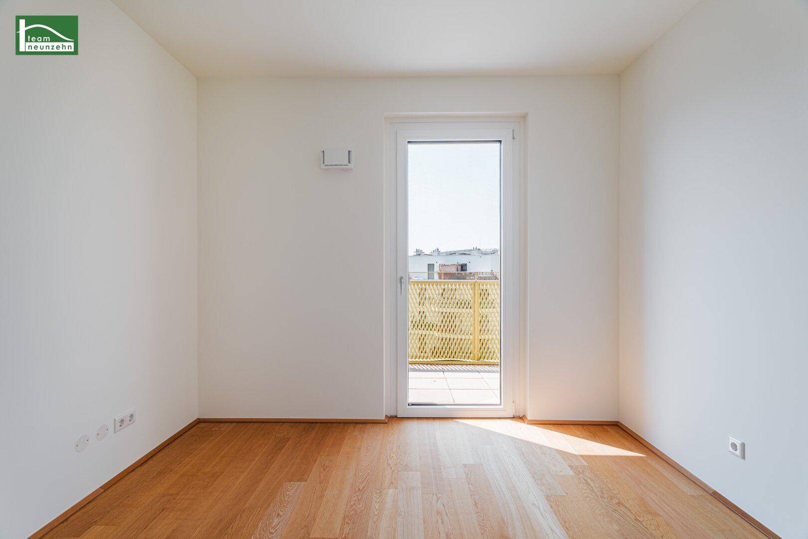 Helles Zimmer mit Holzboden und direktem Zugang zu einem Balkon.