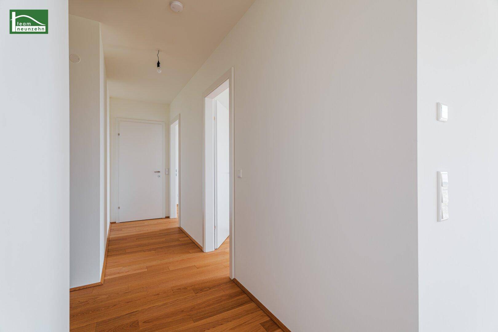 Heller Flur mit Holzboden und mehreren Türen zu den angrenzenden Räumen.
