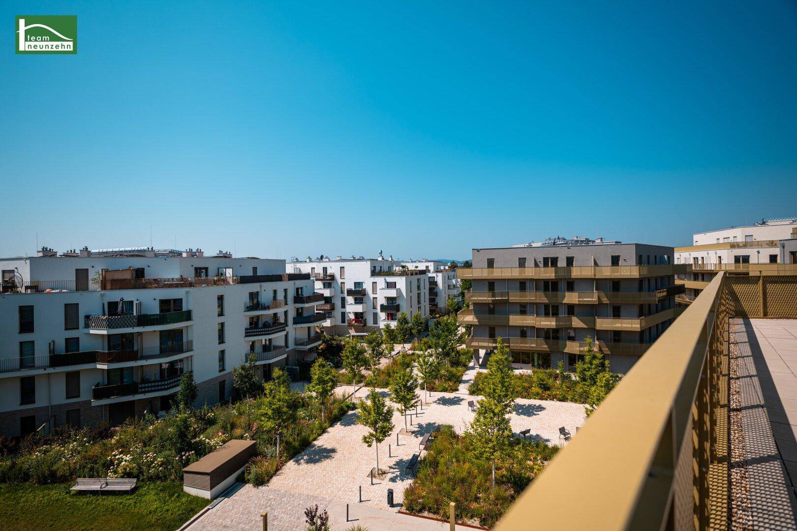Großer Balkon mit Weitblick über die moderne Wohnanlage und Grünflächen.