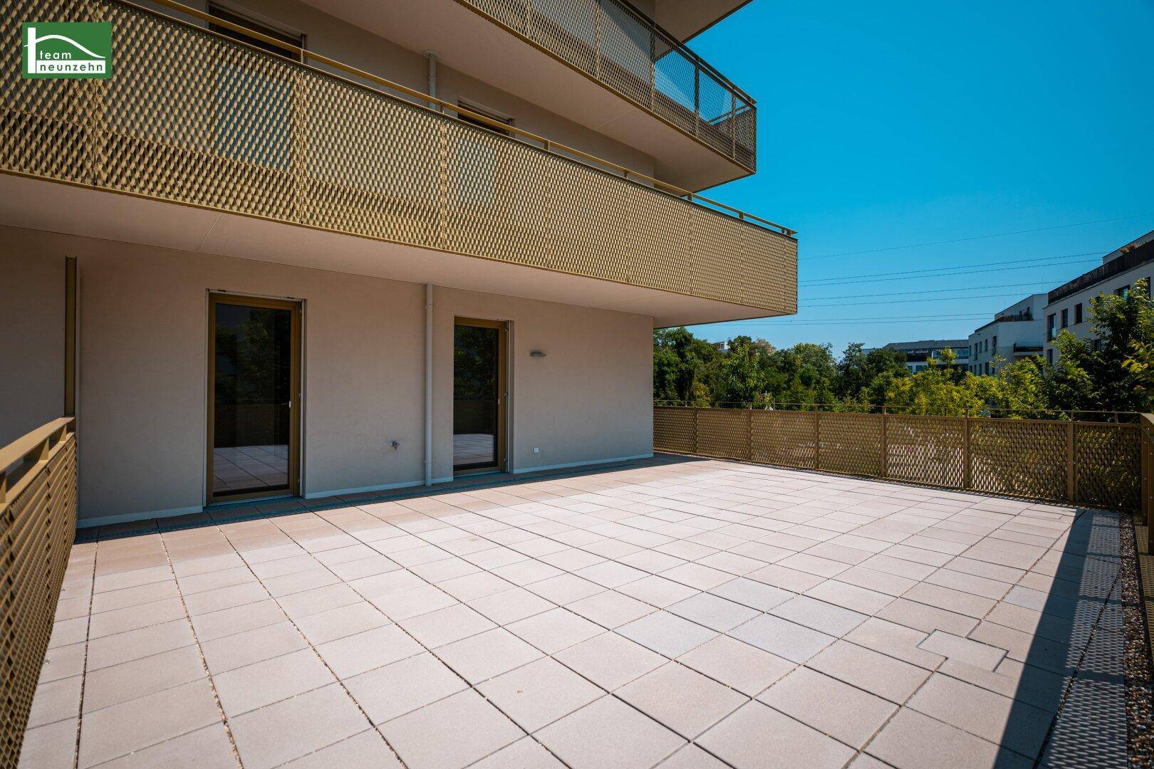Weitläufige Terrasse mit Fliesen und goldfarbenen Geländern, ideal für Entspannung im Freien.