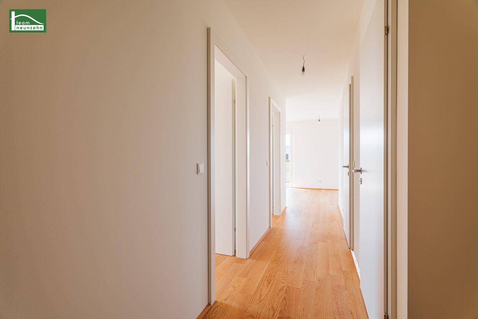 Langer, heller Flur mit Holzboden und mehreren Türen, der verschiedene Räume der Wohnung verbindet.