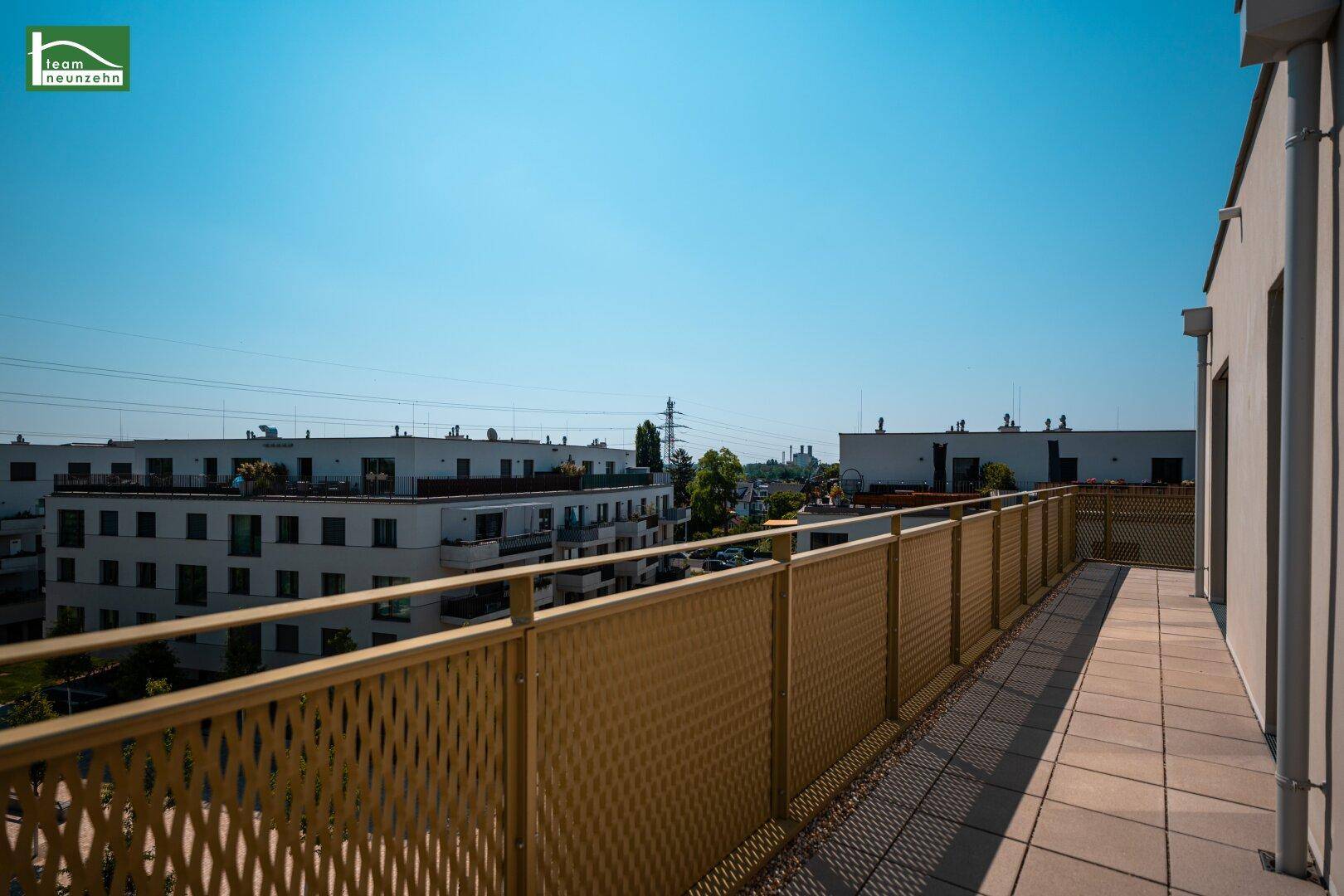 Geräumiger Balkon mit Fliesenboden und Blick auf moderne Wohngebäude in der Umgebung.