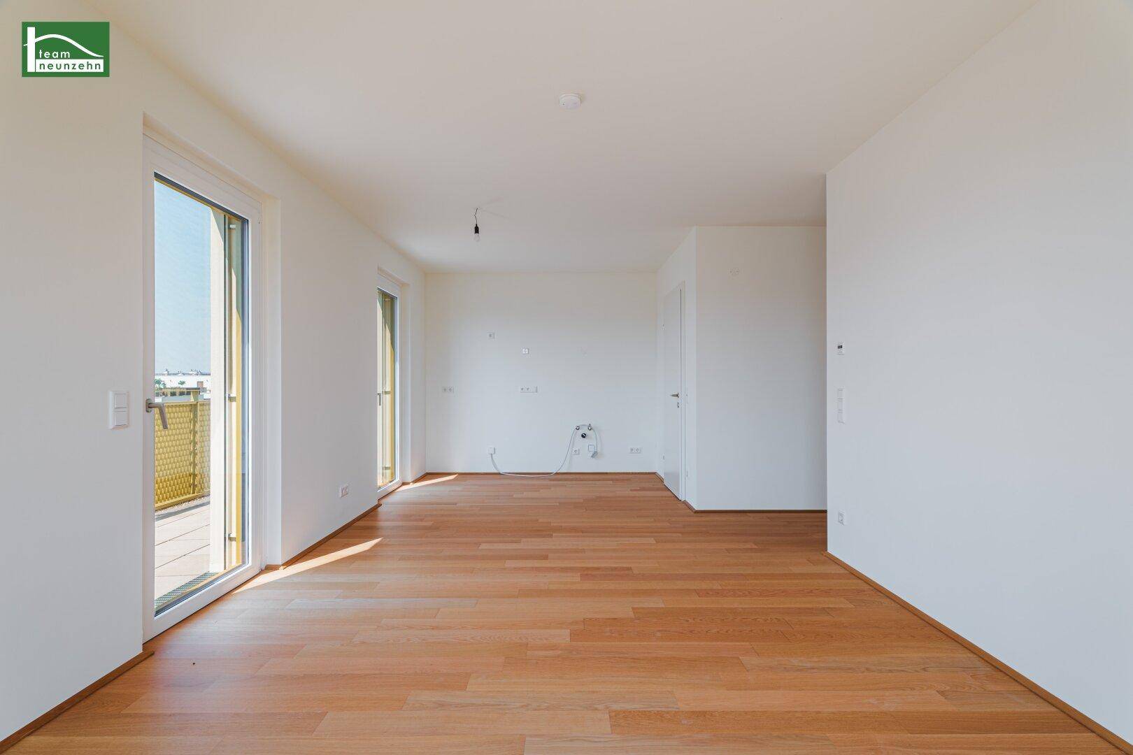 Heller, leerer Raum mit Holzboden und Zugang zu einem Balkon, ideal als Wohnzimmer nutzbar.