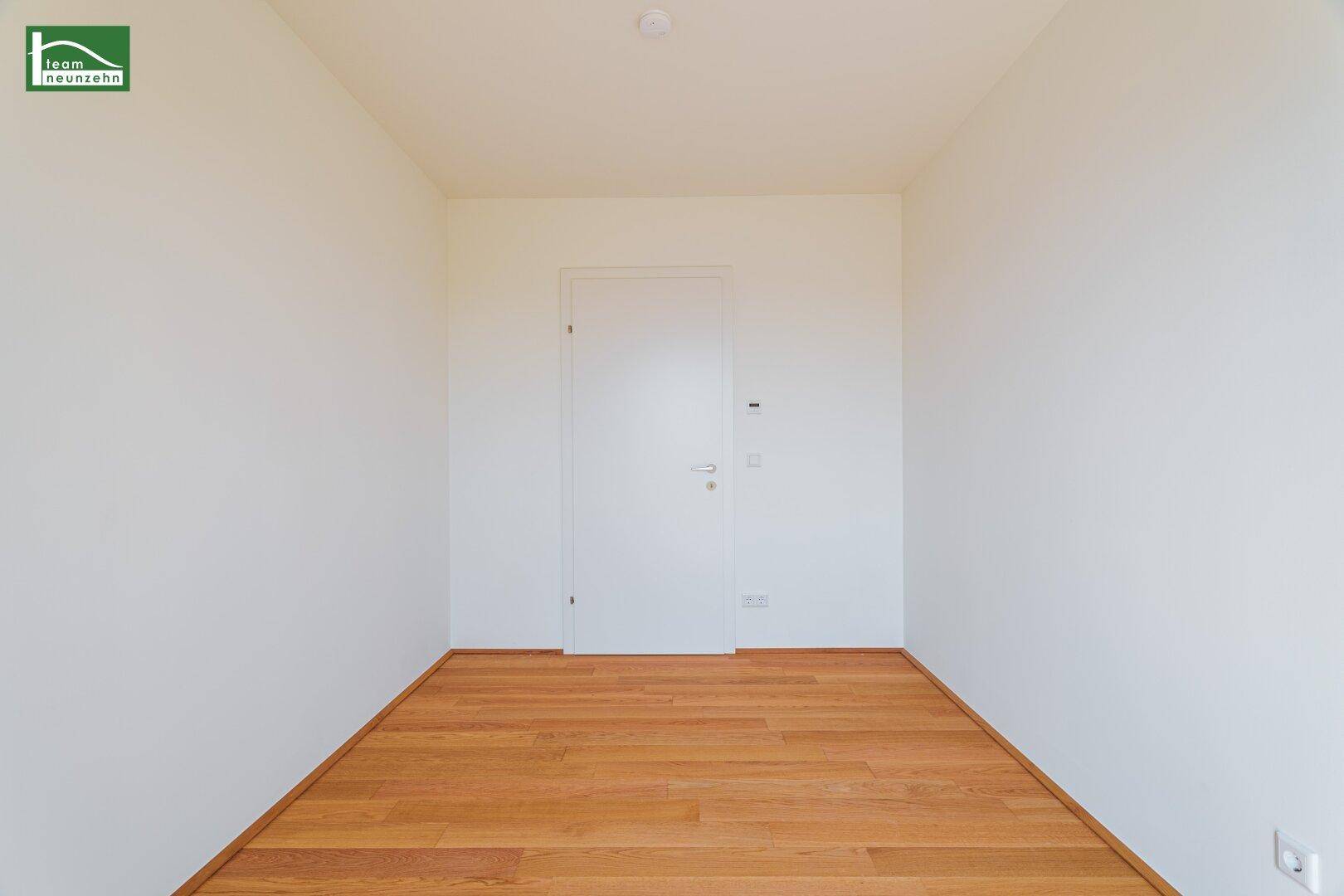 Schlichtes Zimmer mit Holzboden und weißer Tür, das vielseitig genutzt werden kann.