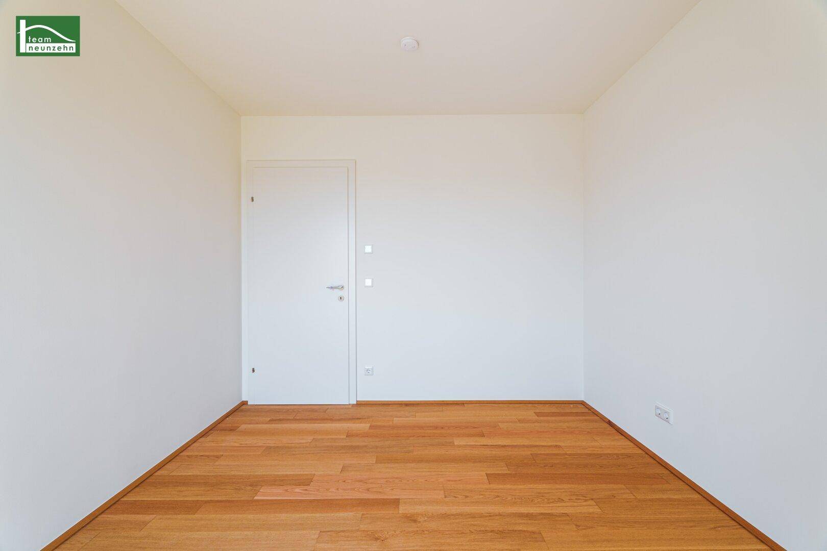 Ruhiges Zimmer mit Holzboden und weiß gestrichenen Wänden, ideal als Schlafzimmer oder Büro.