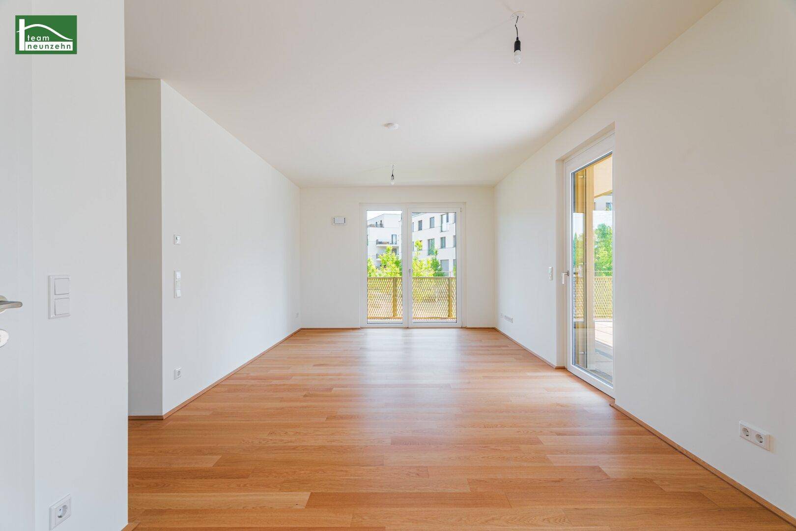 Geräumiges Wohnzimmer mit Holzboden und zwei Zugängen zu Außenbereichen, sehr hell und offen.