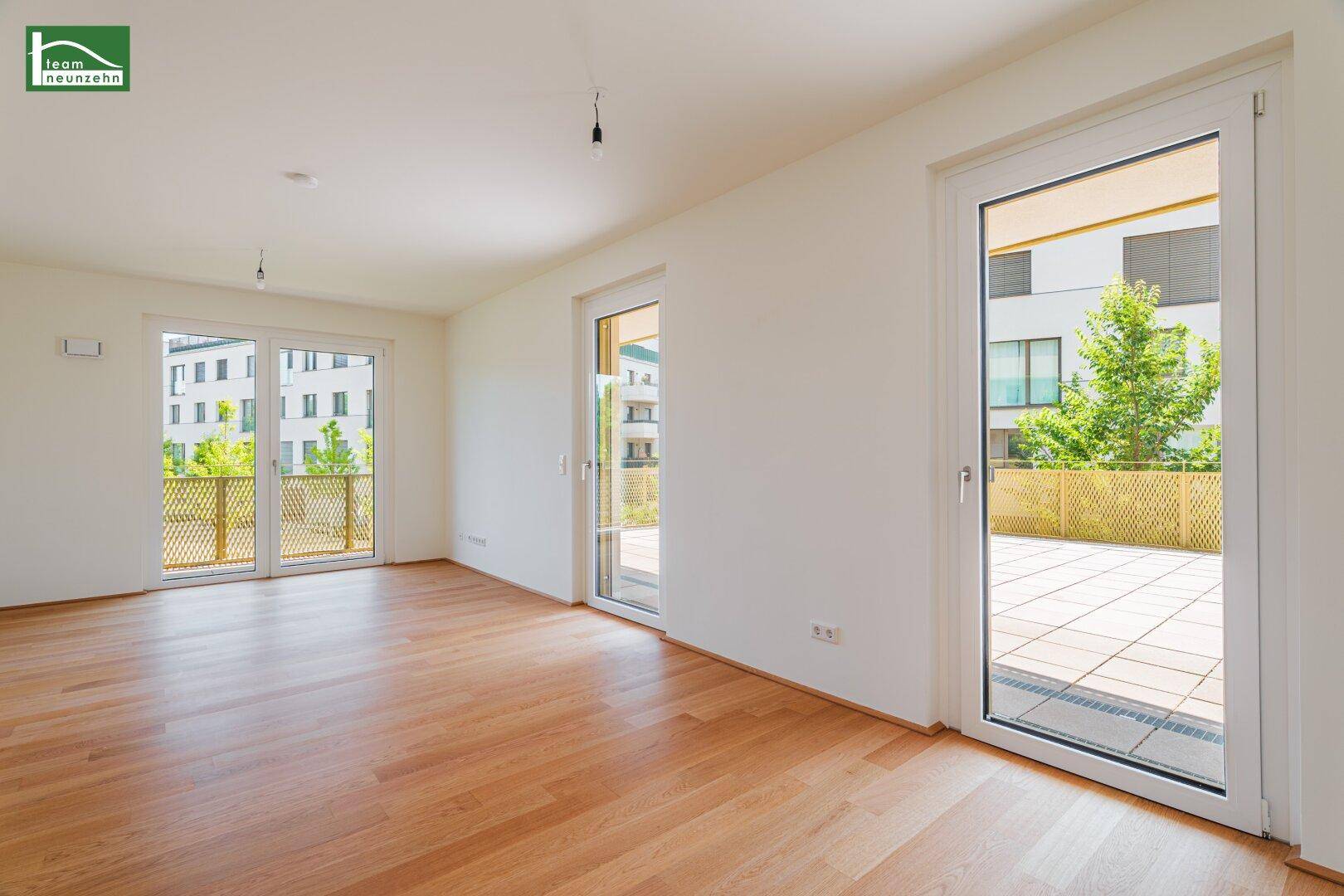 Großes, helles Wohnzimmer mit Holzboden und mehreren Zugängen zu einer Terrasse oder Balkonen.