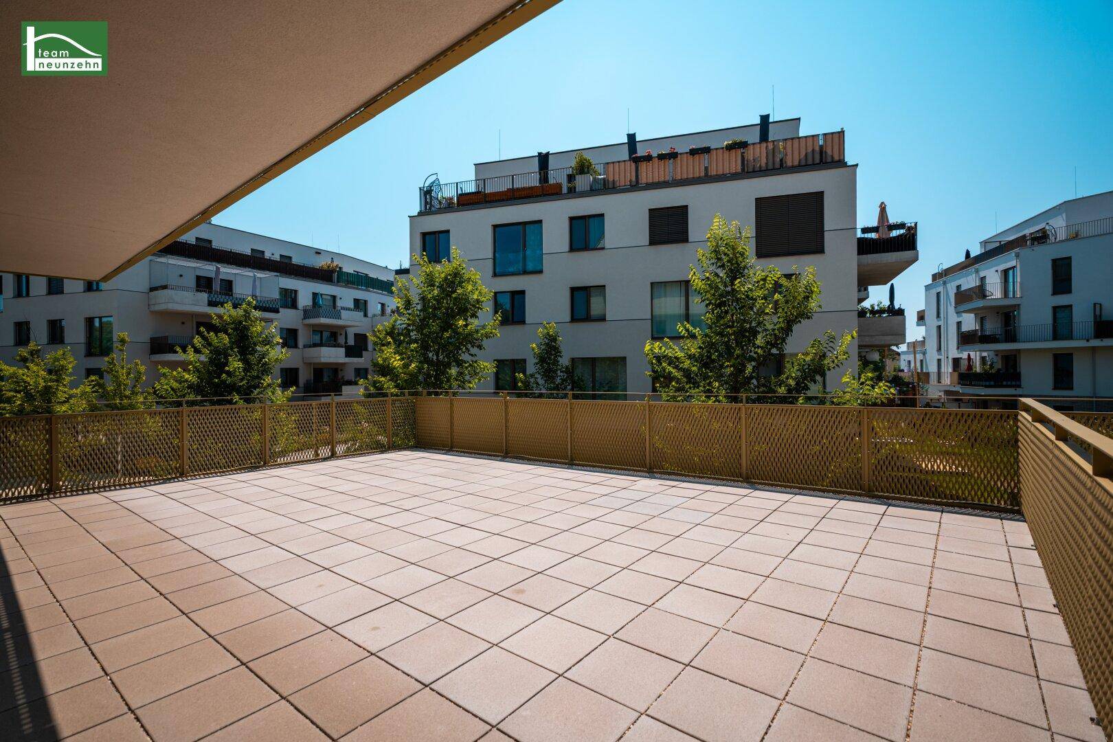 Weitläufige Terrasse mit Fliesenboden und Blick auf die umliegenden modernen Wohngebäude.