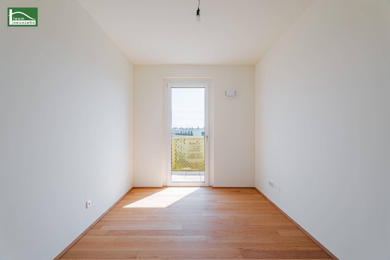 Lichtdurchfluteter Raum mit Holzboden und Balkontür, bietet viel Tageslicht und frische Luft.