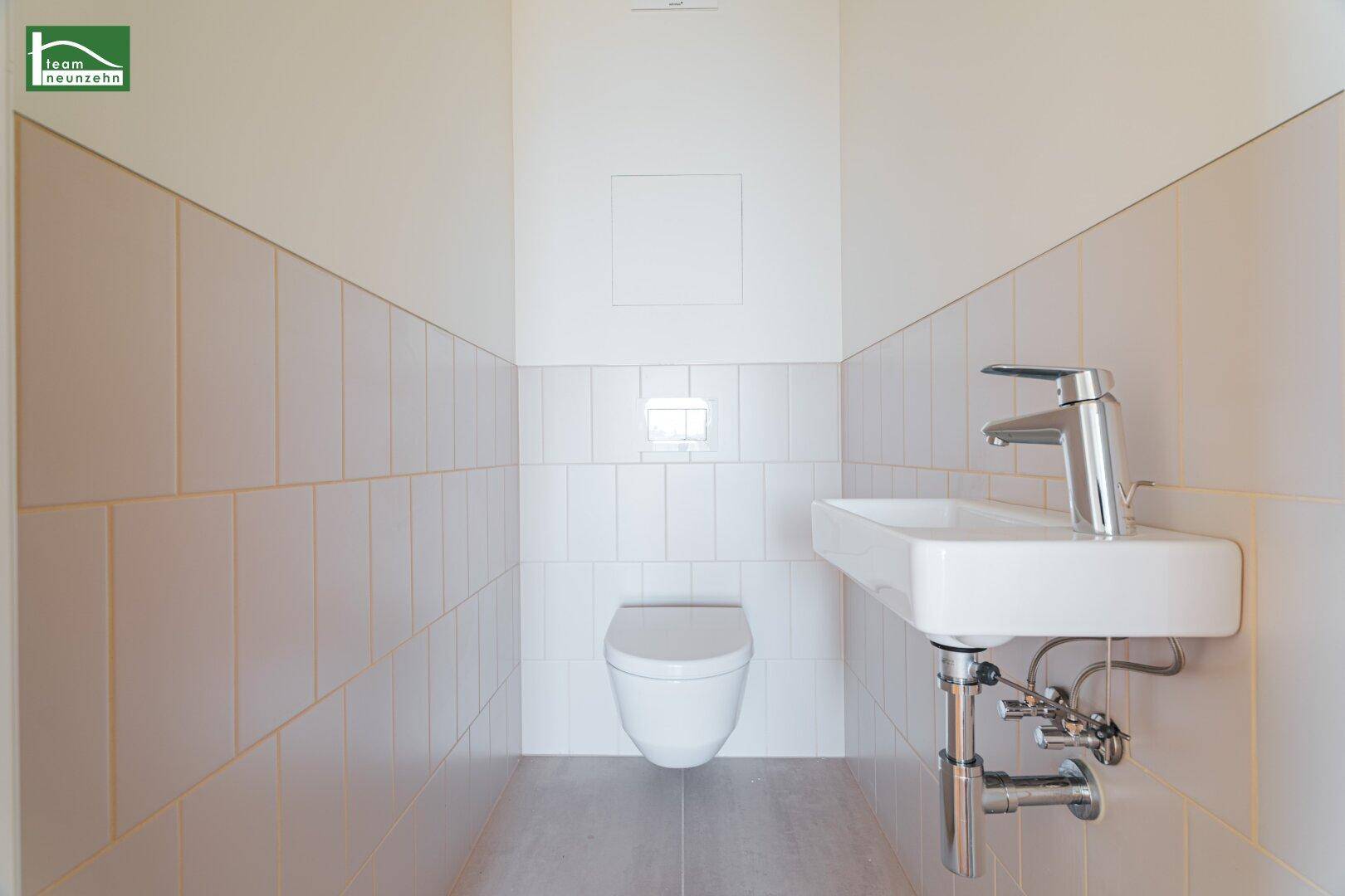 Separates Gäste-WC mit wandhängender Toilette und kleinem Waschbecken, in neutralen Farben.
