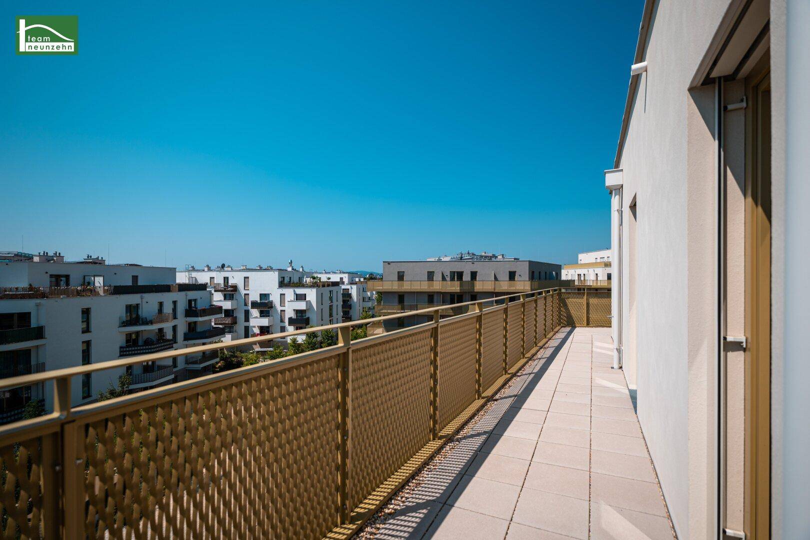 Langer Balkon mit moderner Brüstung und Blick auf die umliegenden Neubaugebäude.