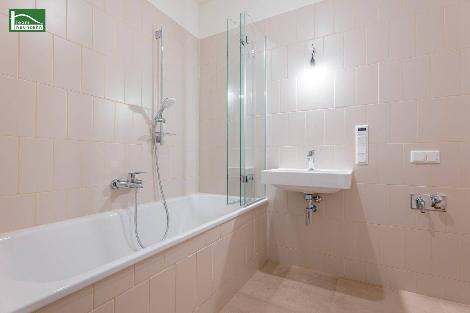 Funktionales Badezimmer mit Badewanne, integrierter Dusche und einem modernen Waschbecken.