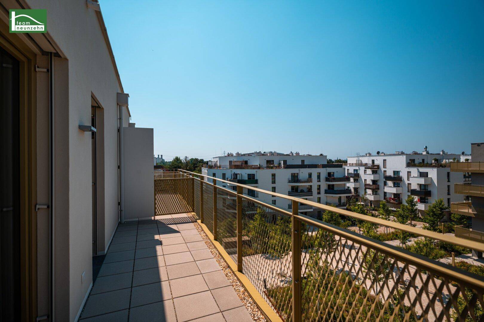 Geräumiger Balkon mit Fliesenboden und Blick auf die umliegenden modernen Wohngebäude.