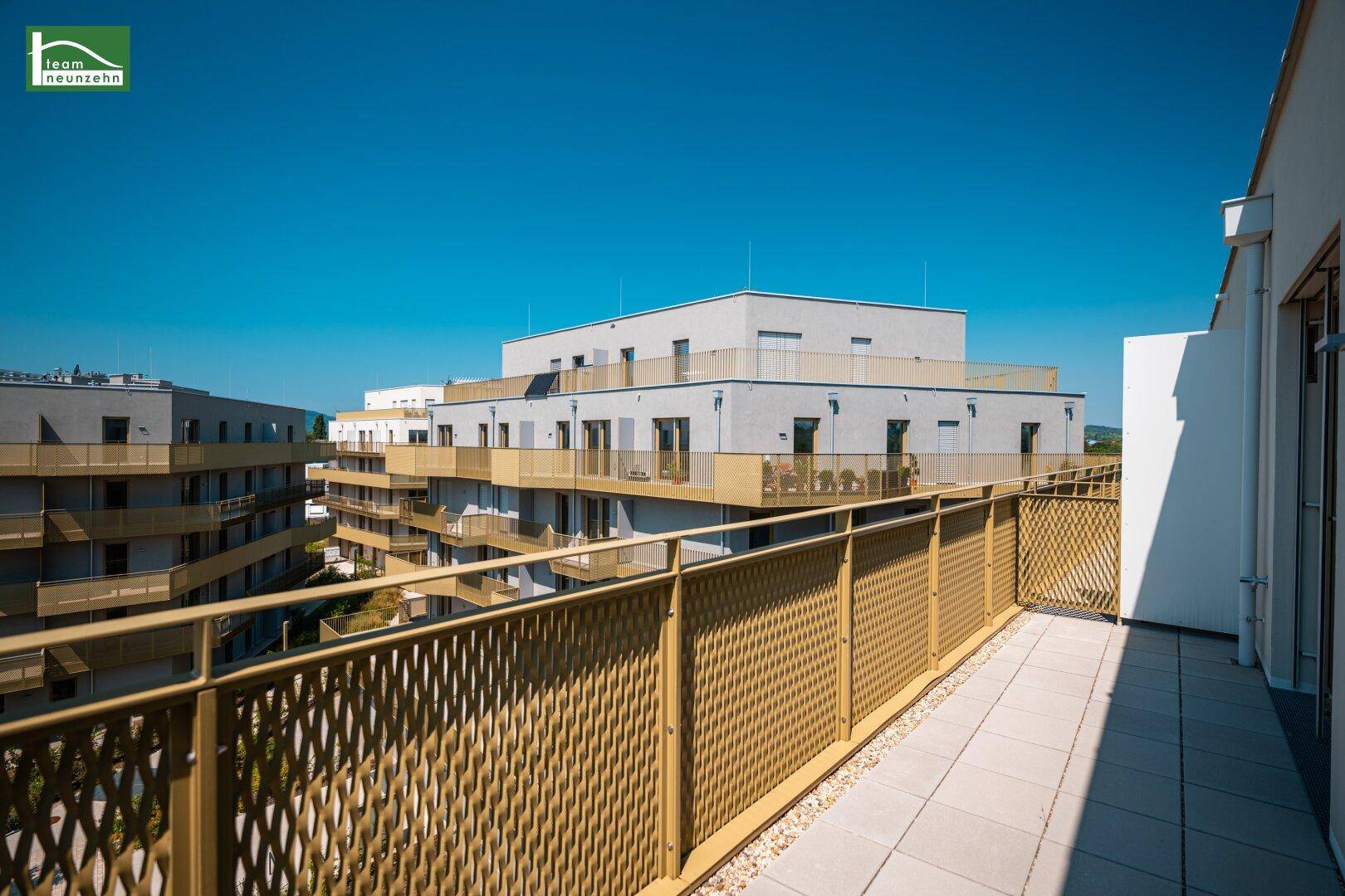 Heller Balkon mit Fliesenboden und einem weiten Blick über die moderne Wohnsiedlung.