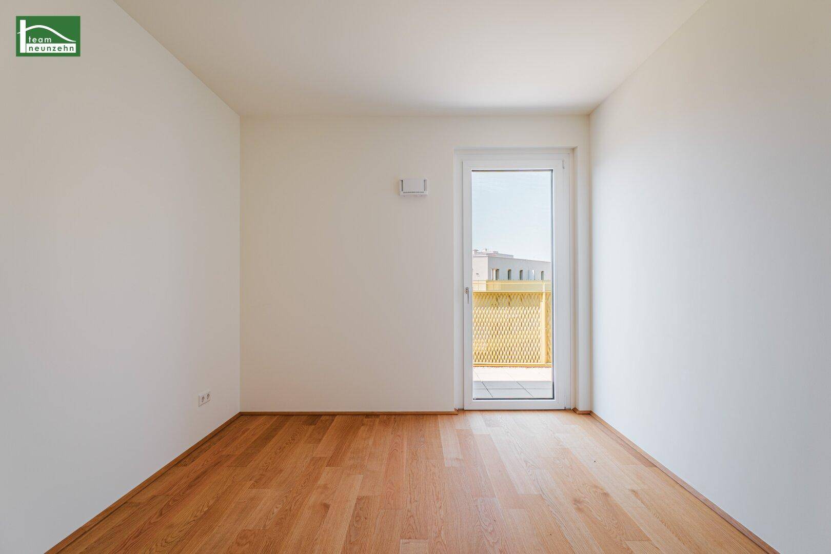 Helles Zimmer mit Holzboden und Zugang zu einem Balkon, ideal für individuelle Gestaltung.