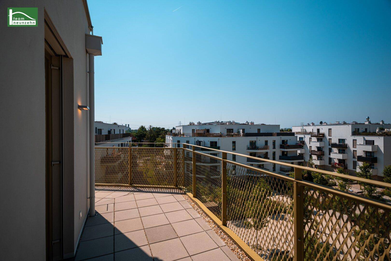 Geräumiger Balkon mit Fliesenboden und moderner Metallbrüstung, bietet Blick auf Wohngebäude.