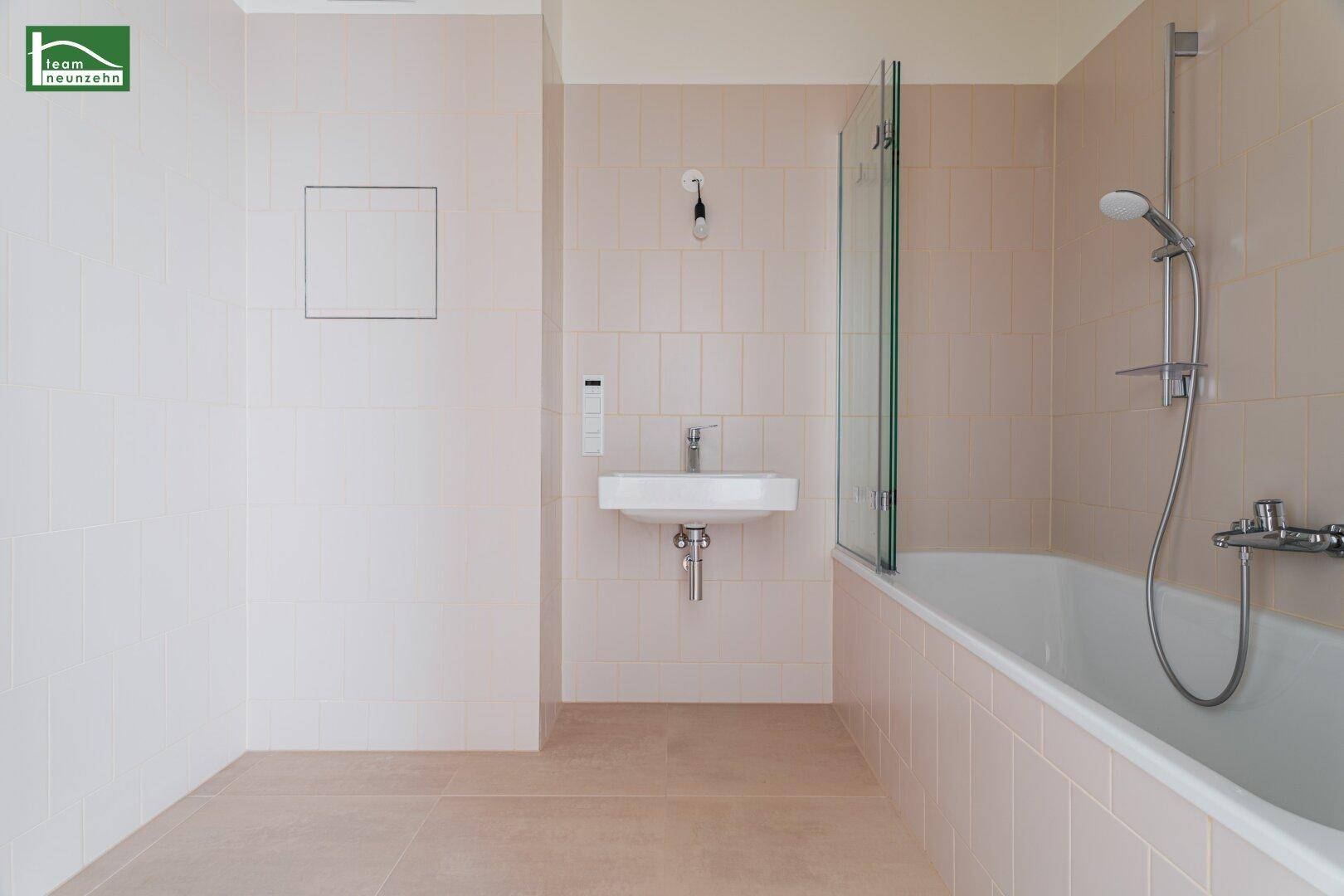 Modernes Badezimmer mit Badewanne, Waschbecken und hellen Fliesen, in neuwertigem Zustand.