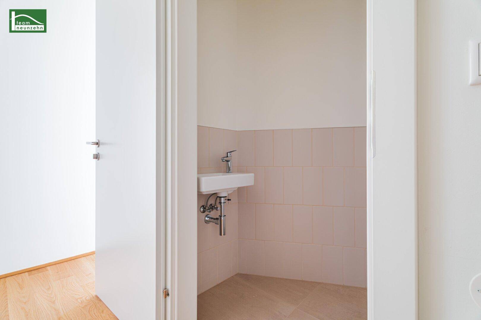 Kleines Gäste-WC mit Waschbecken und hellen Fliesen, funktional und sauber.
