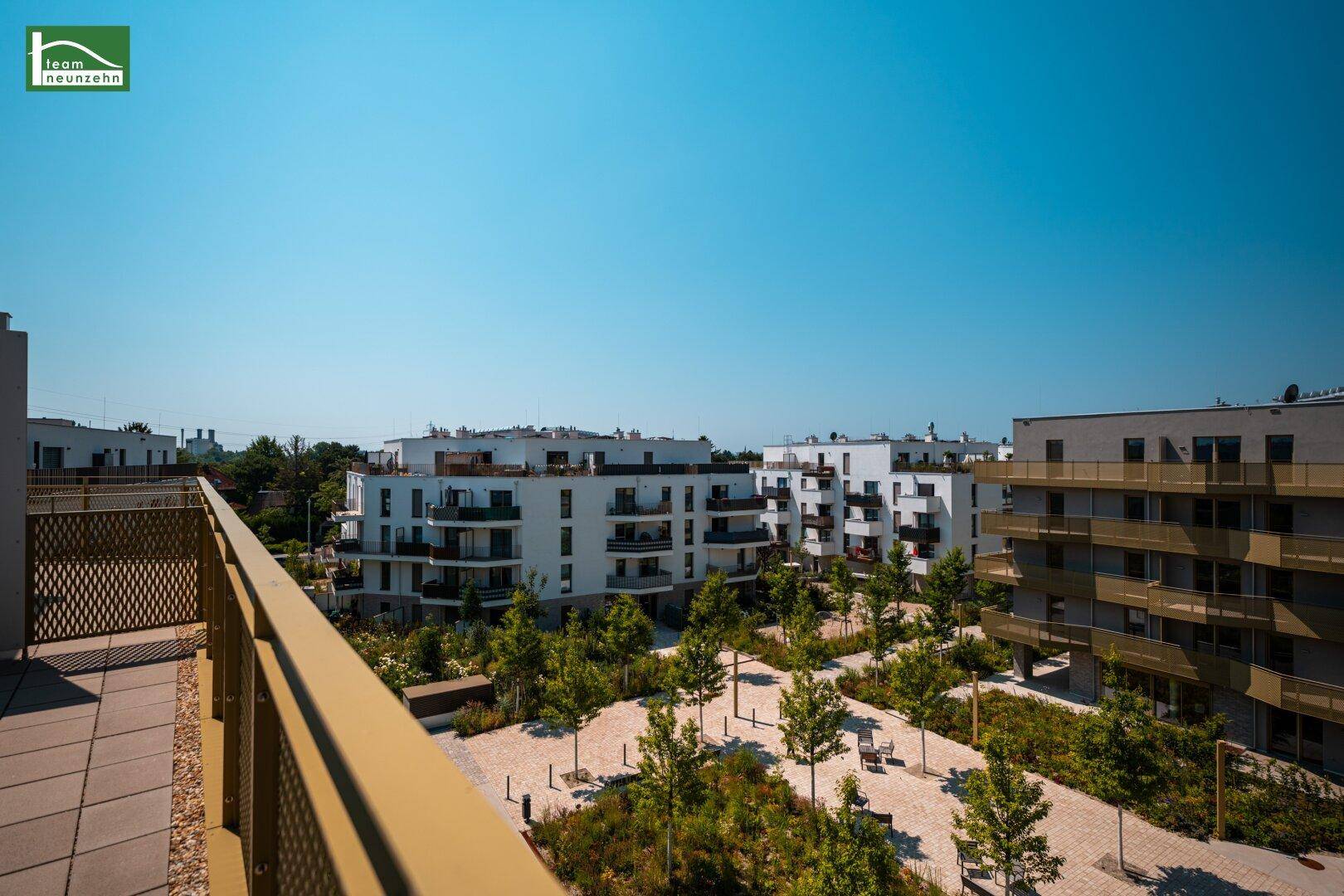 Balkon mit Ausblick auf die gepflegte Grünanlage und weitere Wohngebäude der Siedlung.