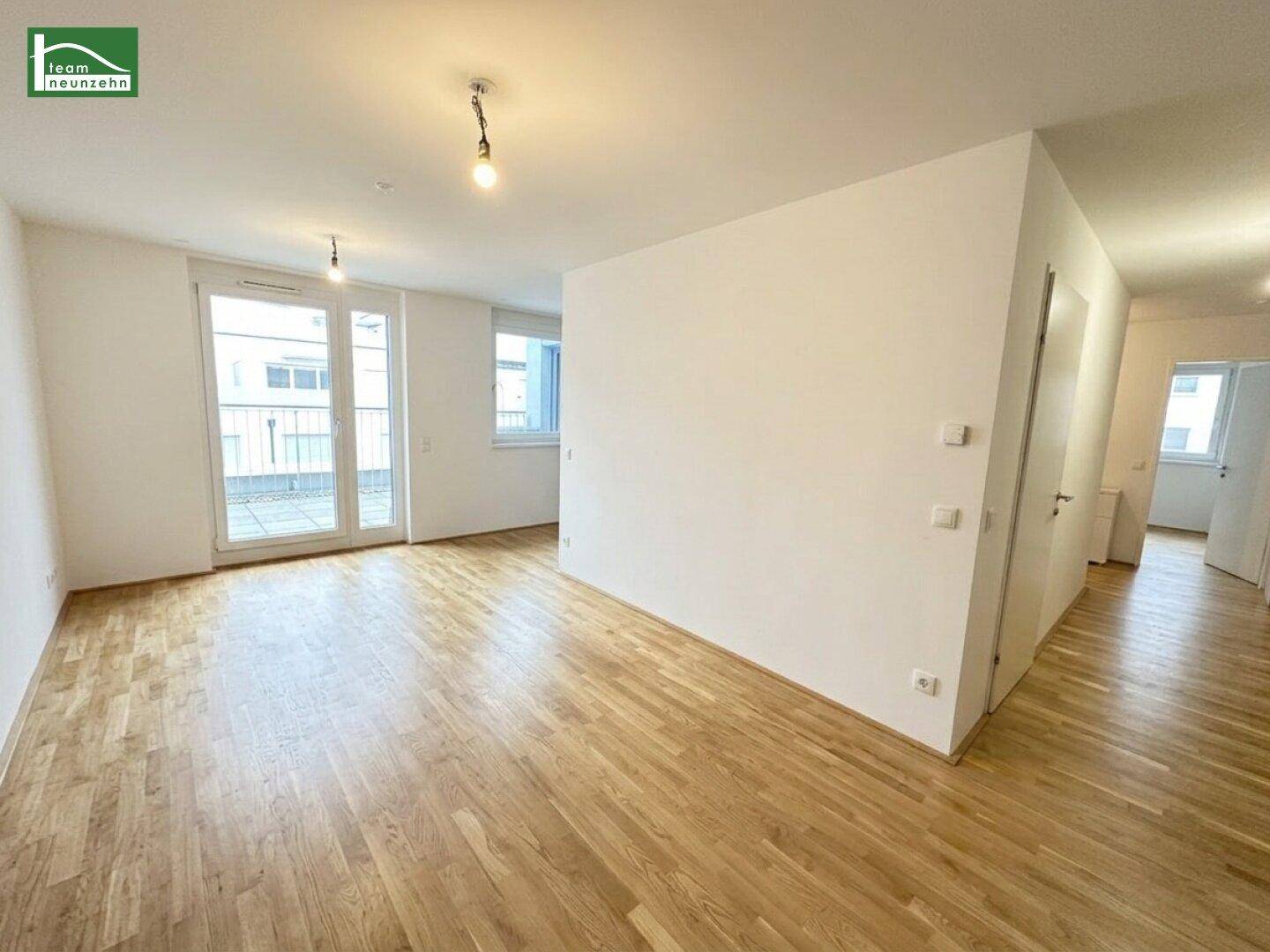Geräumiges Wohnzimmer mit Parkettboden und großen Fenstern, die viel Tageslicht hereinlassen.
