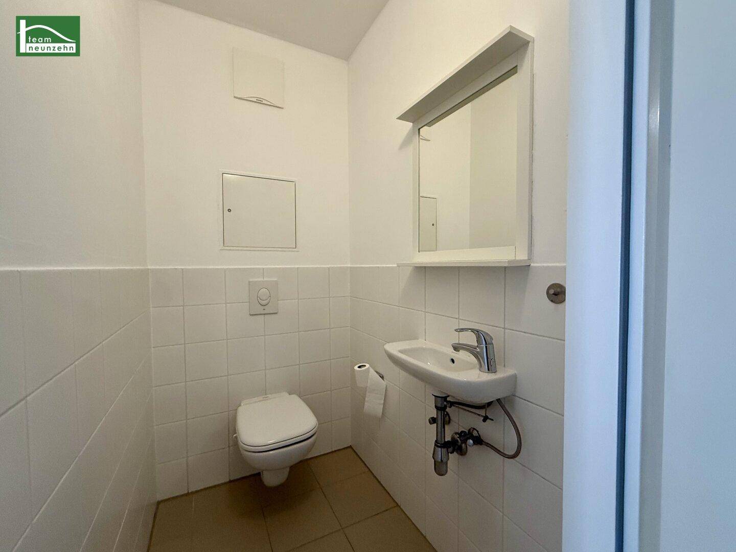 Kleines Gäste-WC mit weißen Fliesen, wandhängendem WC und Waschbecken.