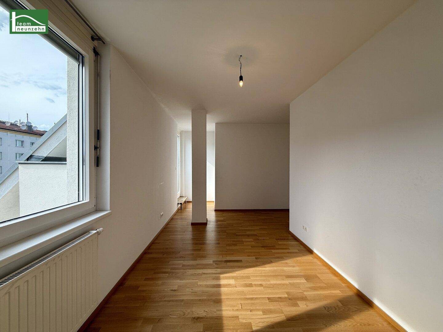 Langer Flur mit Parkettboden, weißen Wänden und natürlichem Lichteinfall.