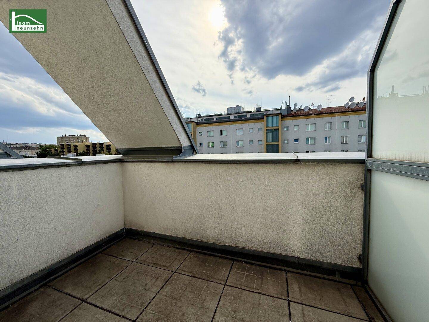 Dachterrasse mit Fliesenboden und Blick auf die umliegende Stadtlandschaft.