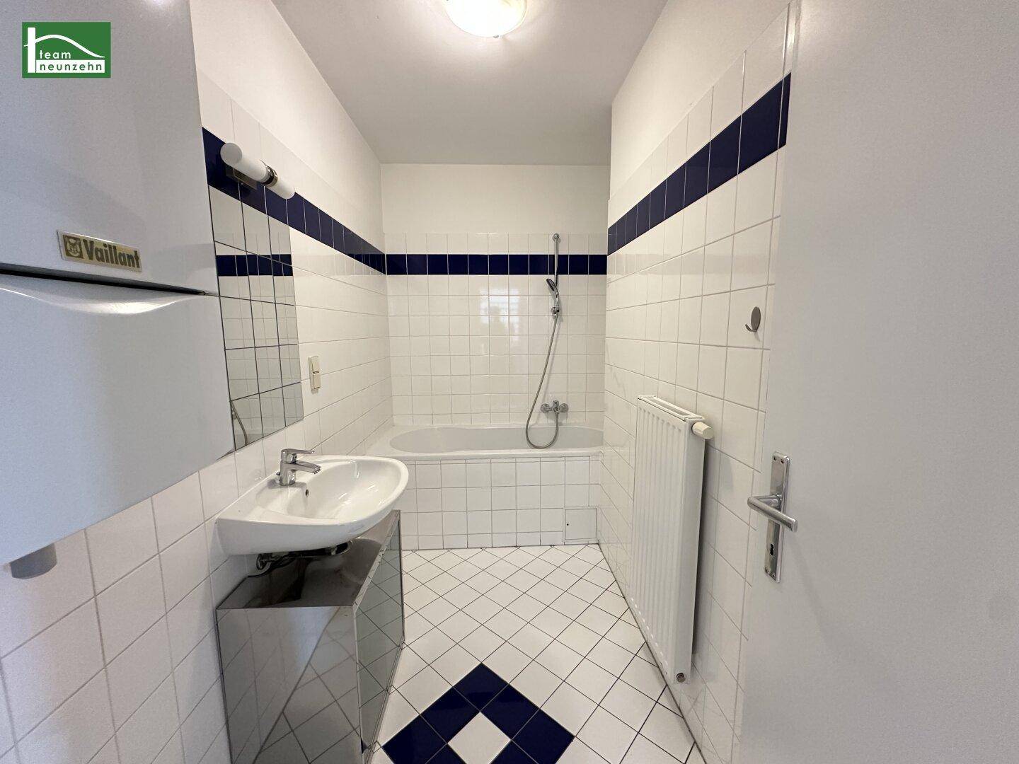 Gefliestes Badezimmer mit Badewanne, Waschbecken und Heizkörper.