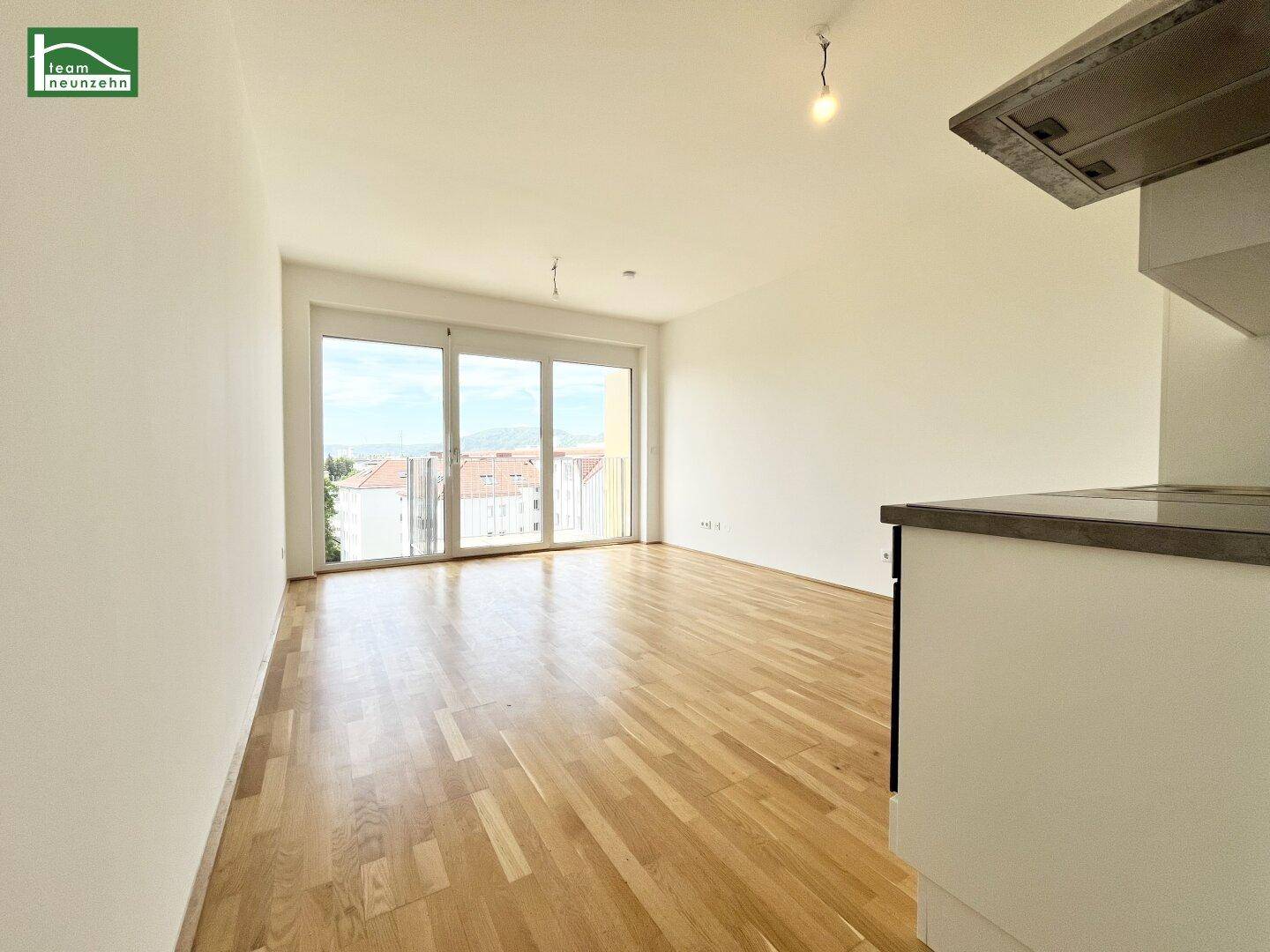 Heller Wohnbereich mit Parkettboden und großen Schiebetüren, die auf einen Balkon führen.