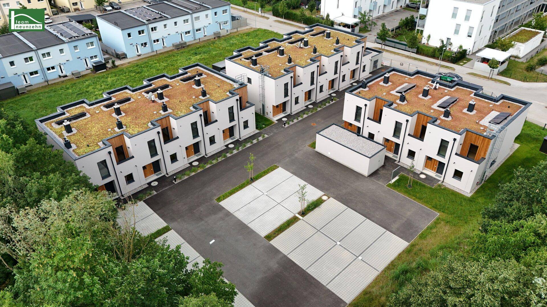 Nahaufnahme von modernen Reihenhäusern mit begrünten Flachdächern und zugehörigen Parkplätzen.
