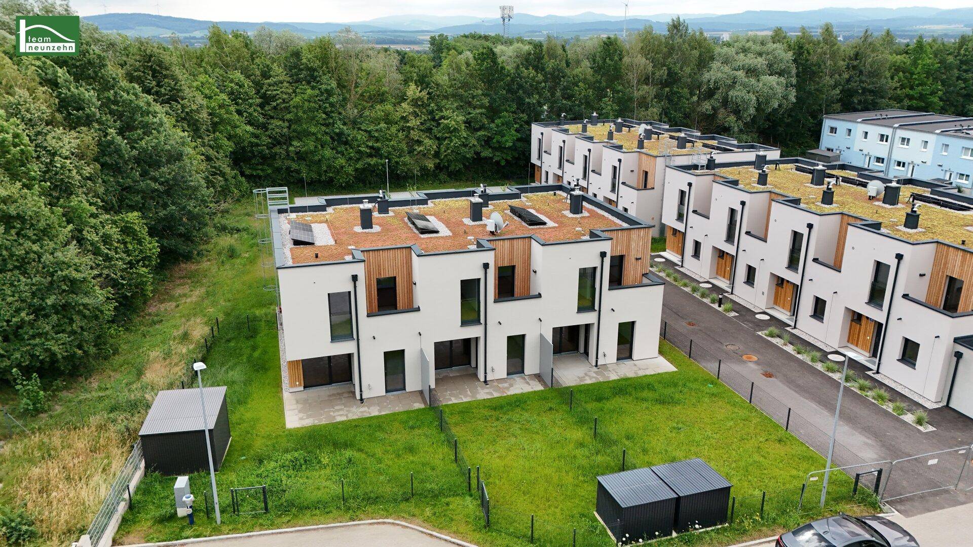 Reihen moderner Häuser mit Gründächern, Holzfassadenelementen und kleinen privaten Grünflächen.
