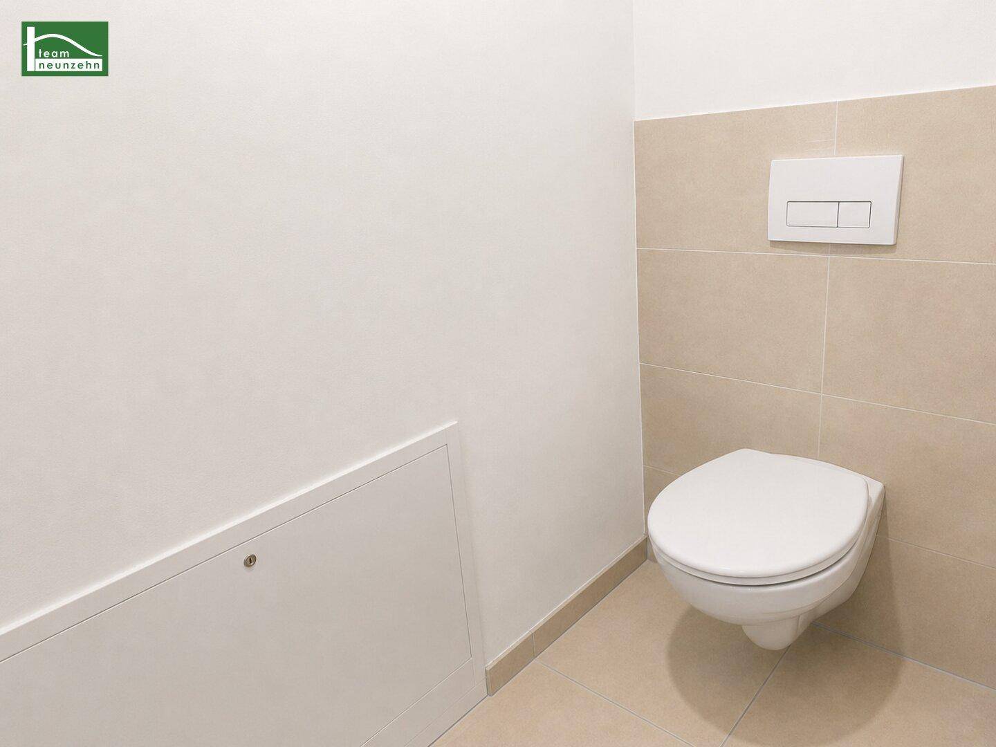 Separates WC mit wandhängender Toilette und modernen beigefarbenen Fliesen im unteren Bereich.